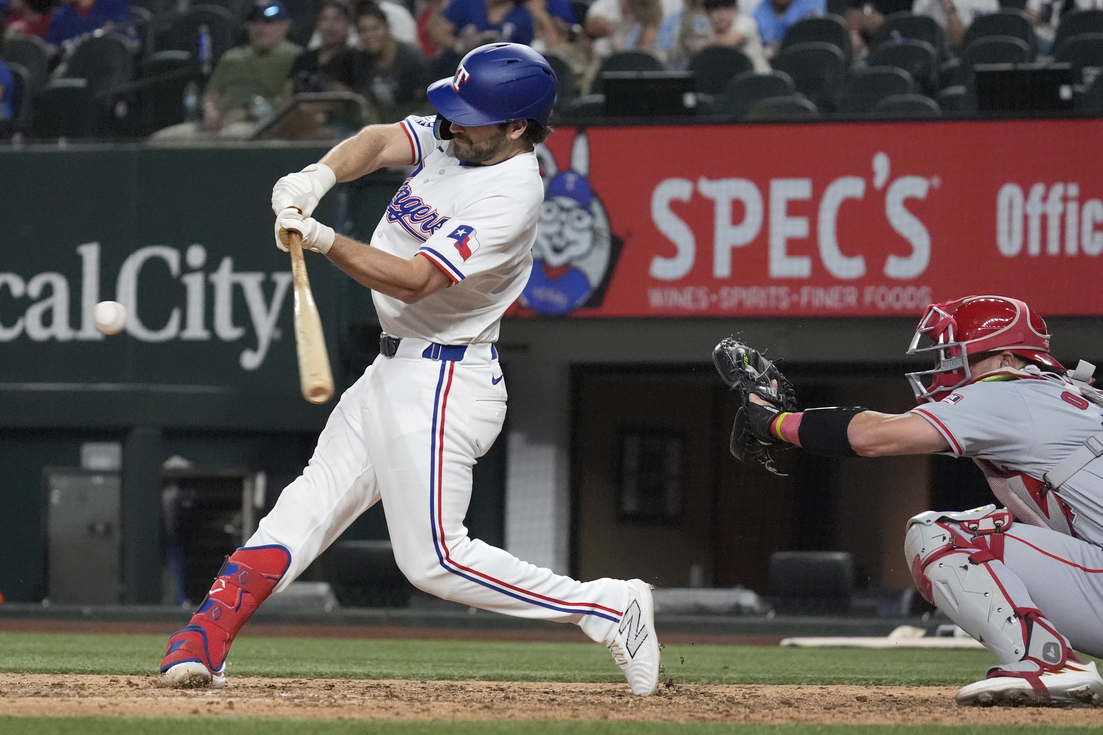 Texas Rangers' Josh Smith, left, hits a single in front of Los Angeles Angels catcher Logan O'Hoppe, right, that scored Carson Kelly and Marcus Semien during the seventh inning of a baseball game Saturday, Sept. 7, 2024, in Arlington, Texas.