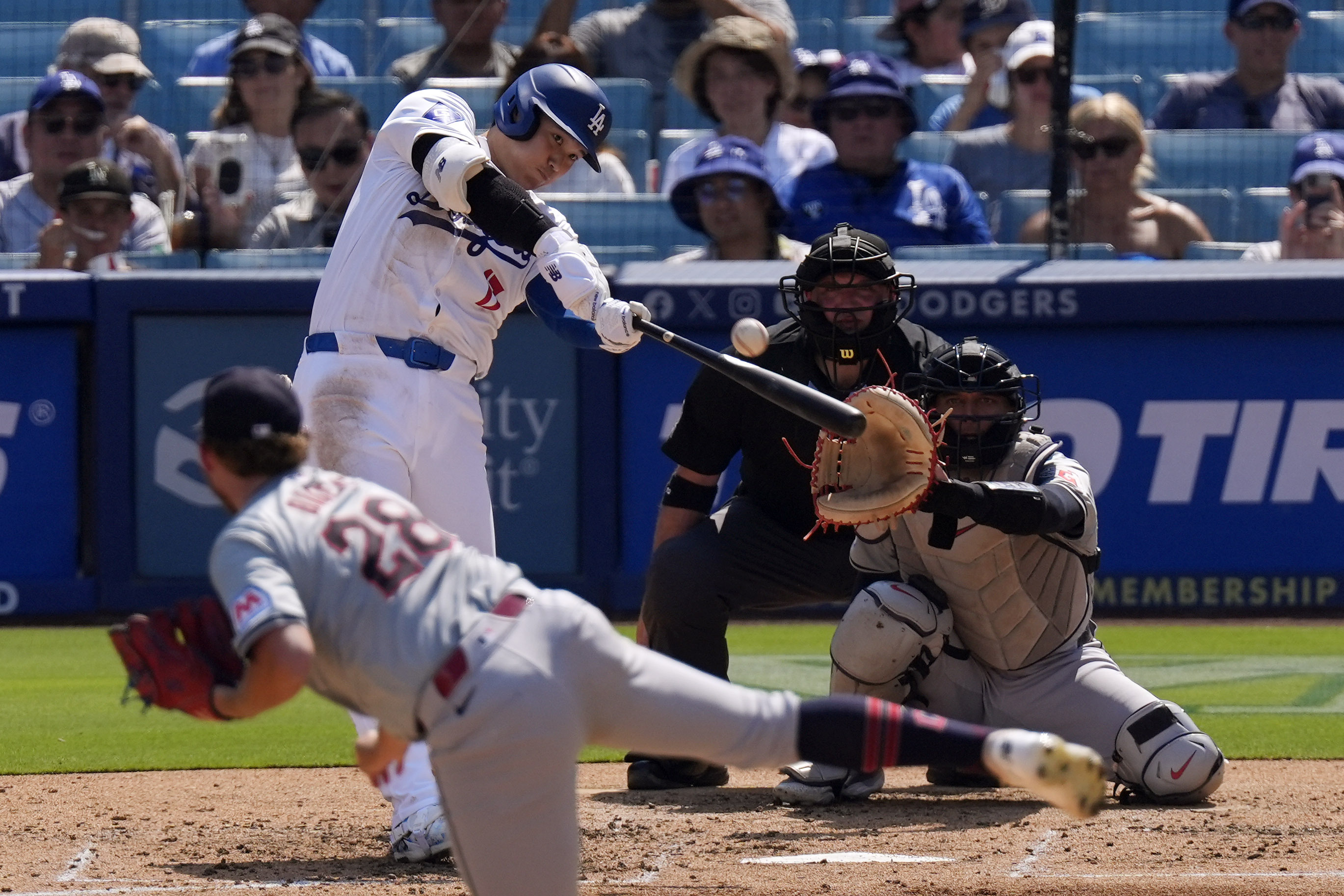 Los Angeles Dodgers' Shohei Ohtani, second from left, hits a solo home run as Cleveland Guardians starting pitcher Tanner Bibee, left, watches along with catcher Bo Naylor, right, and home plate umpire Dan Bellino during the fifth inning of a baseball game, Sunday, Sept. 8, 2024, in Los Angeles.
