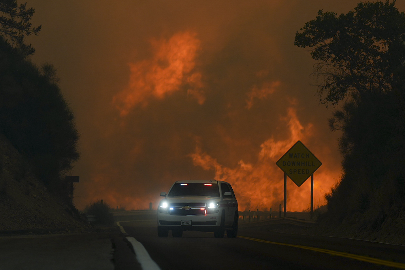 The Line Fire jumps Highway 330 as an emergency vehicle is driven past near Running Springs, Calif. on Saturday.