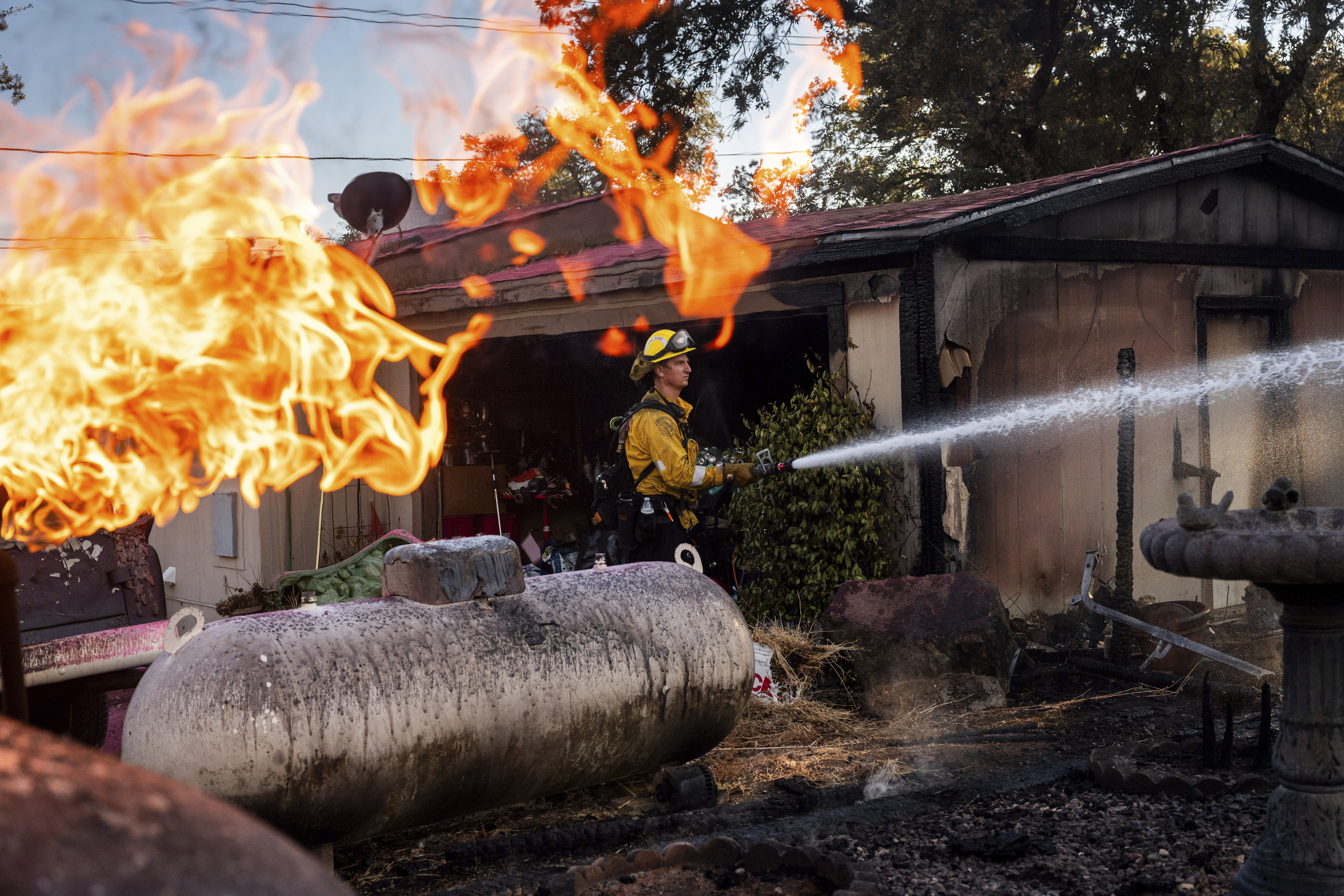 Firefighter Nolan Graham sprays water around a scorched garage as the Boyles fire burns in Clearlake, Calif., on Sunday. Thousands of people have been evacuated from the path of a scorching wildfire in the foothills of a national forest east of Los Angeles as the blaze threatens some 36,000 structures.