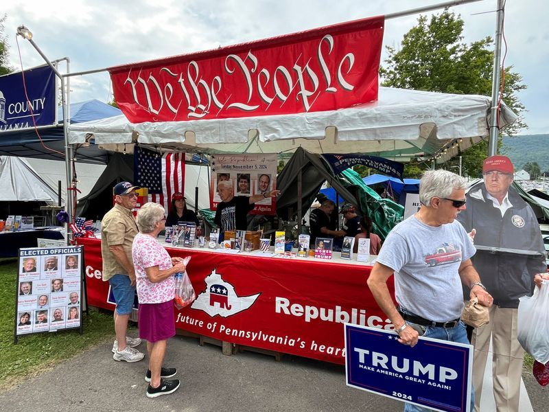 People gather in front of the booth set up by the Centre County Republican Party to register and engage with potential voters at the Grange Fair, an annual fair and camping event in Centre Hall, Pa., Aug. 16.