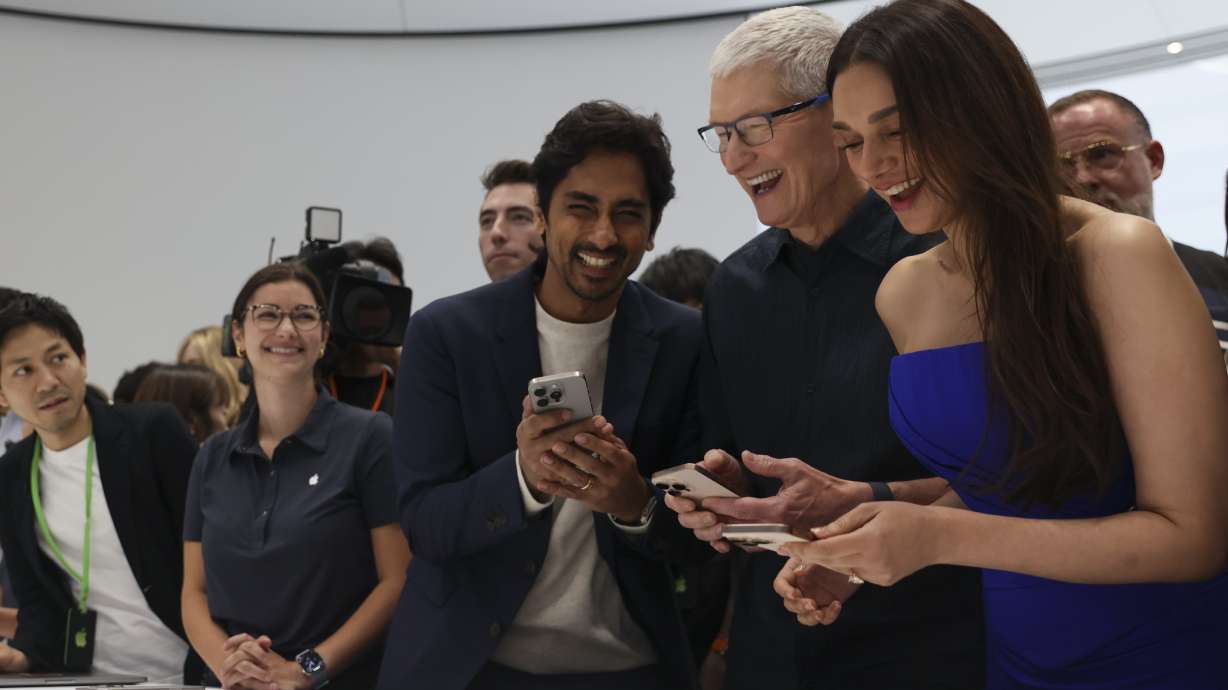 Apple CEO Tim Cook, second from right, smiles as he shows the new iPhone 16 model to attendees at Apple headquarters Monday in Cupertino, Calif.