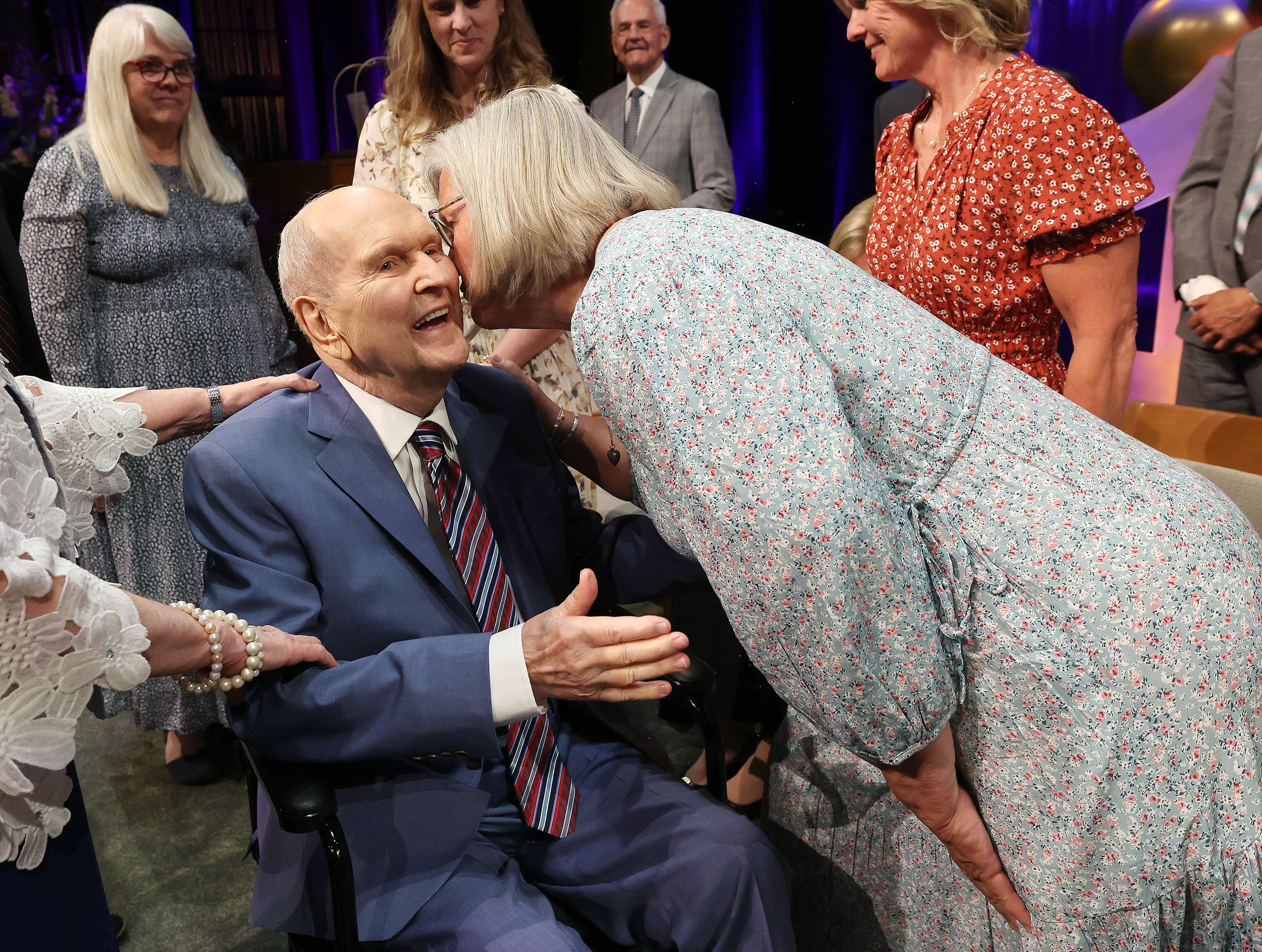 President Russell M. Nelson of The Church of Jesus Christ of Latter-day Saints is kissed by his daughter Gloria Irion during his 100th birthday celebration at the Little Theatre of the Conference Center in Salt Lake City on Monday.