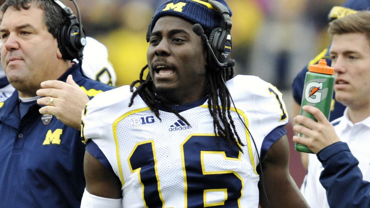 FILE - Michigan head coach Brady Hoke, left, and quarterback Denard Robinson, right, call over the offense during a timeout in the third quarter of an NCAA college football game against Minnesota, Saturday, Nov. 3, 2012, in Minneapolis.