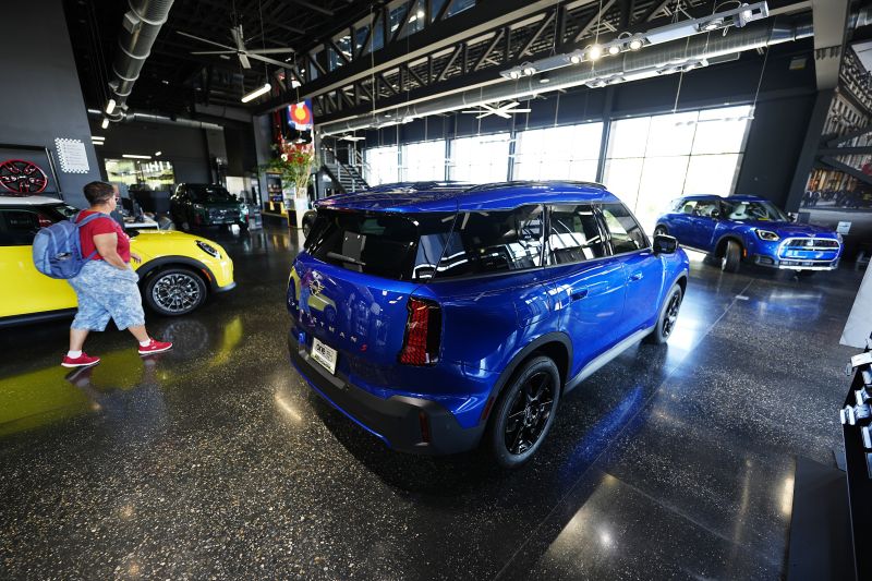 A shopper looks over an unsold 2025 Cooper S hardtop on display with Countryman S utility vehicles in the showroom of a Mini dealership, Sept. 4, in Highlands Ranch, Colo.