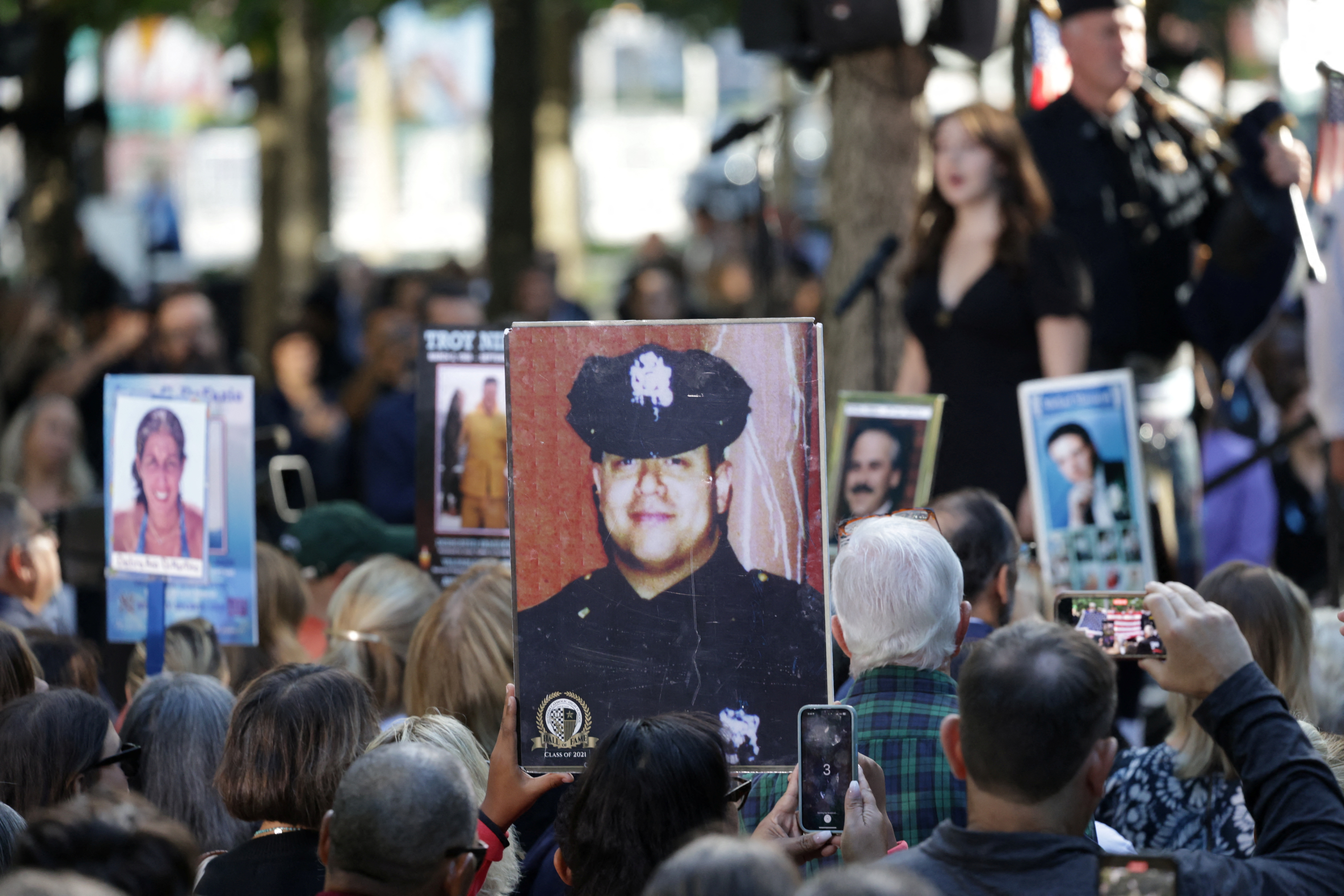 A woman sings the U.S. national anthem as people attend a ceremony marking the 23rd anniversary of the Sept. 11, 2001, attacks on the World Trade Center at the 9/11 Memorial and Museum in the Manhattan borough of New York City, Wednesday.