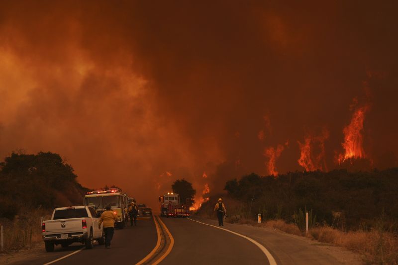 Firefighters monitor the Airport Fire as it advances Tuesday, in El Cariso, an unincorporated community in Riverside County, Calif.