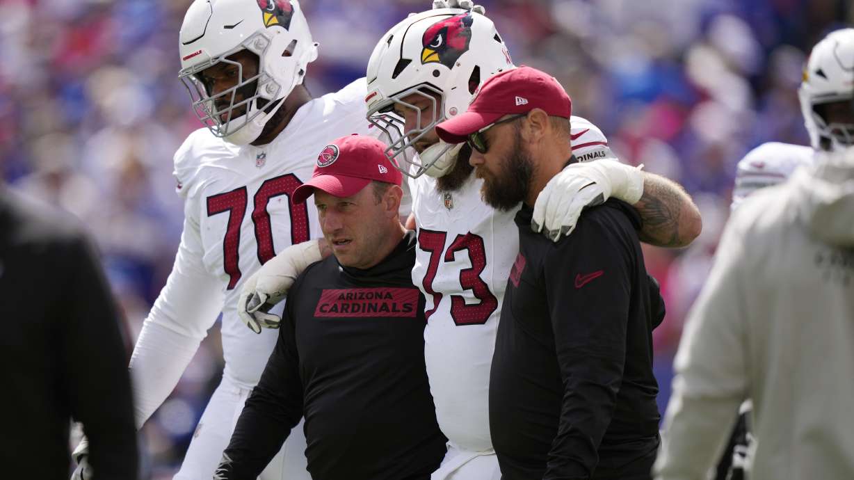 Arizona Cardinals offensive tackle Jonah Williams (73) gets helped off the field as Cardinals offensive tackle Paris Johnson Jr. (70) pats him on the helmet during the first half of an NFL football game against the Buffalo Bills Sunday, Sept. 8, 2024, in Orchard Park, N.Y.