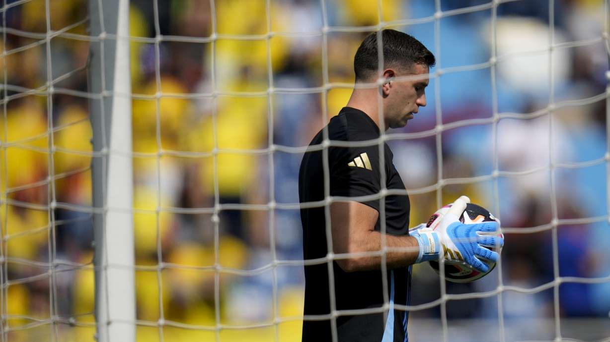 Argentina's goalkeeper Emiliano Martinez holds a ball while warming up prior to a qualifying soccer match against Colombia for the FIFA World Cup 2026 at the Metropolitano Roberto Melendez stadium in Barranquilla, Colombia, Tuesday, Sept. 10, 2024.