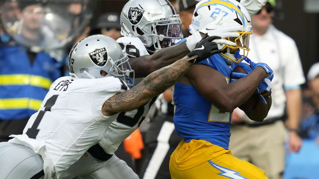 Los Angeles Chargers running back J.K. Dobbins, right, runs against Las Vegas Raiders safety Marcus Epps, left, and cornerback Nate Hobbs during the second half of an NFL football game, Sunday, Sept. 8, 2024, in Inglewood, Calif.