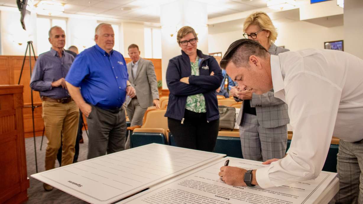 Ogden City Council Chairman Ken Richey signs an oversized version of the Ogden Community Engagement Charter in City Council chambers on Tuesday. Other council members look on.