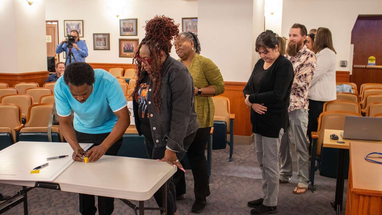 Members of the public and others prepare to sign an oversized version of the Ogden Community Engagement Charter at City Council chambers on Tuesday.
