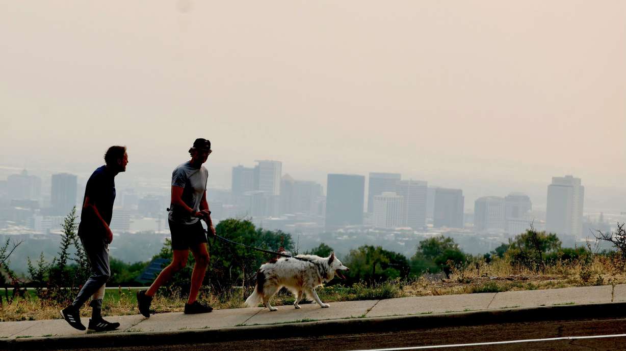 Two men walk their dogs as smoke fills the Salt Lake Valley Wednesday. The smoke is coming from wildfires in the western U.S.