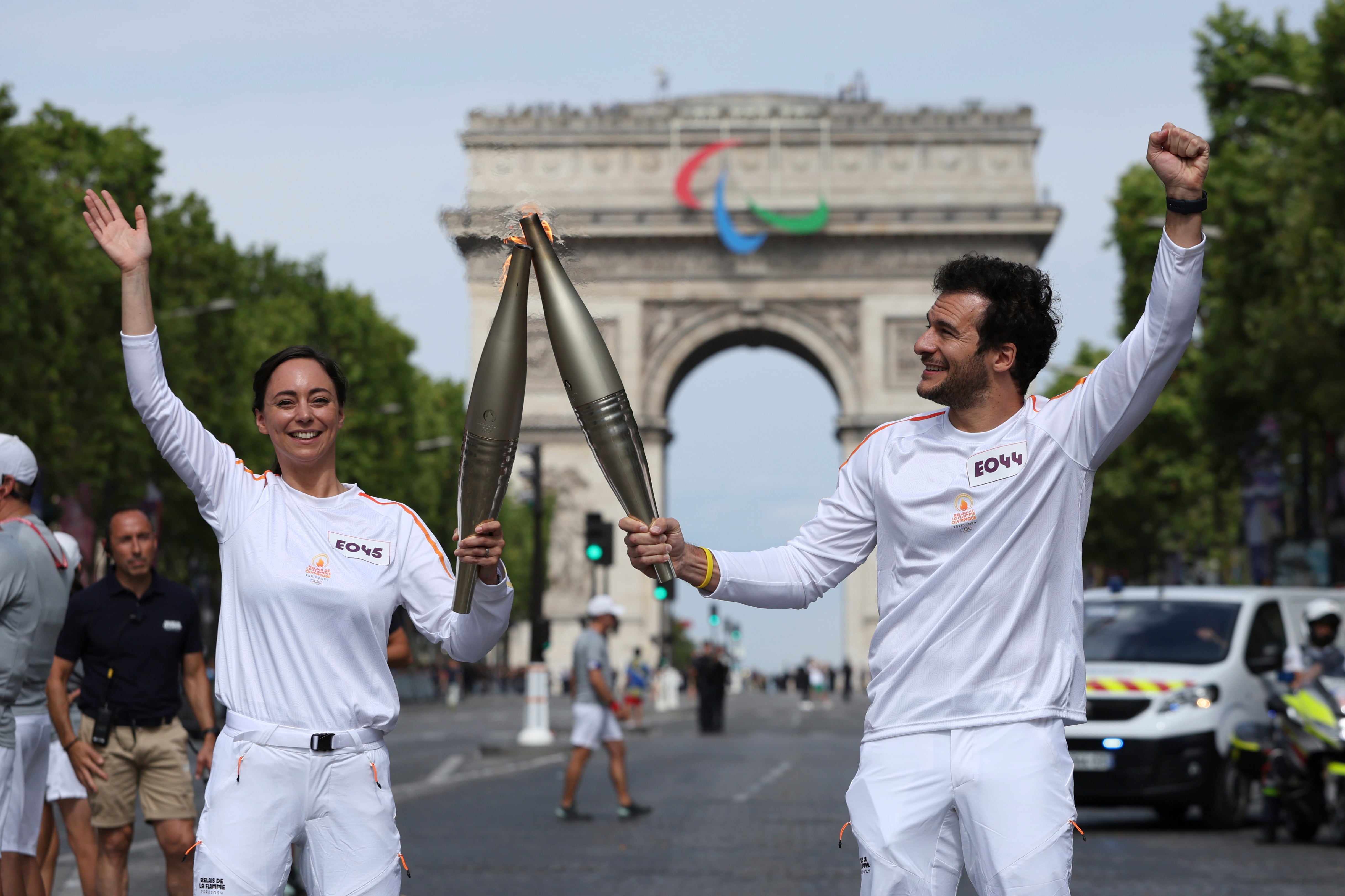 Torchbearers Nina Metayer, and French-Israeli singer Amir hold the Olympic torch on the Champs-Elysees avenue, July 15 in Paris, 11 days before the French capital hosted the Paris Olympic Games.