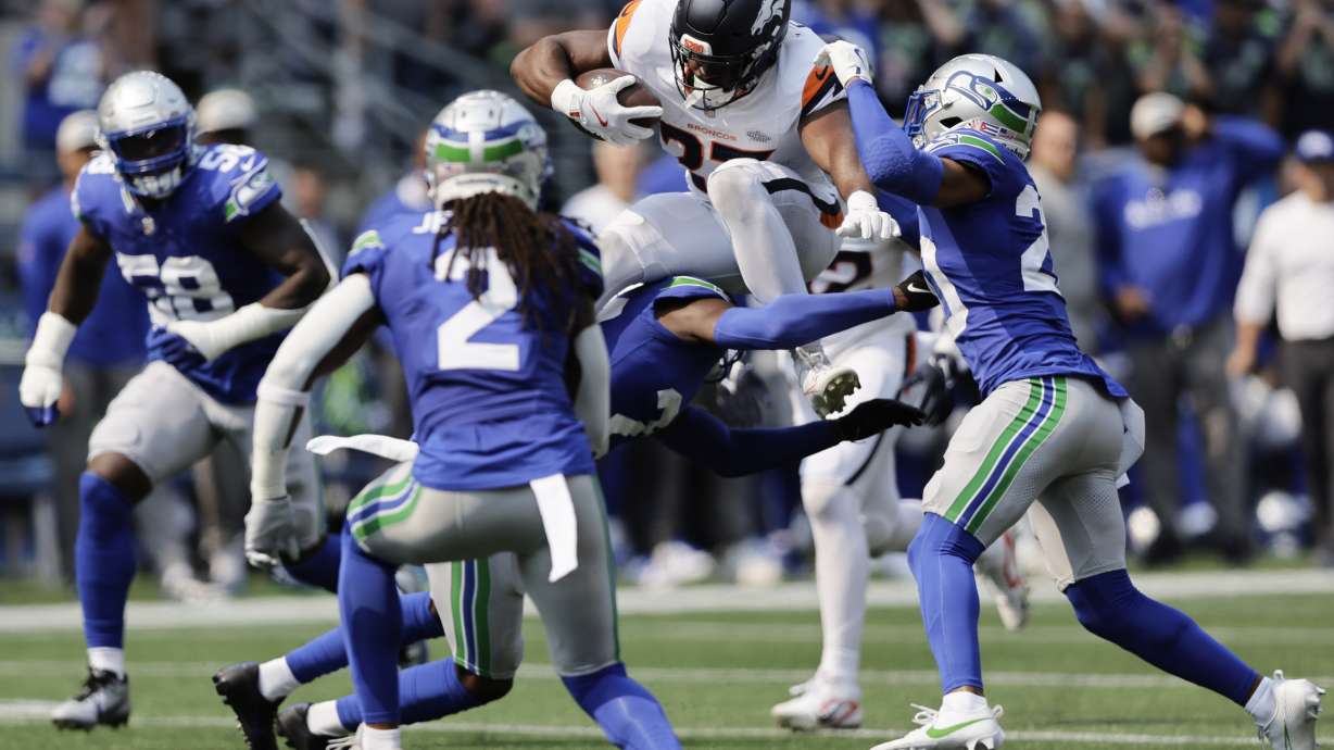 Denver Broncos running back Audric Estime (23) leaps over Seattle Seahawks safety Julian Love (20) during the first half of an NFL football game Sunday, Sept. 8, 2024, in Seattle.