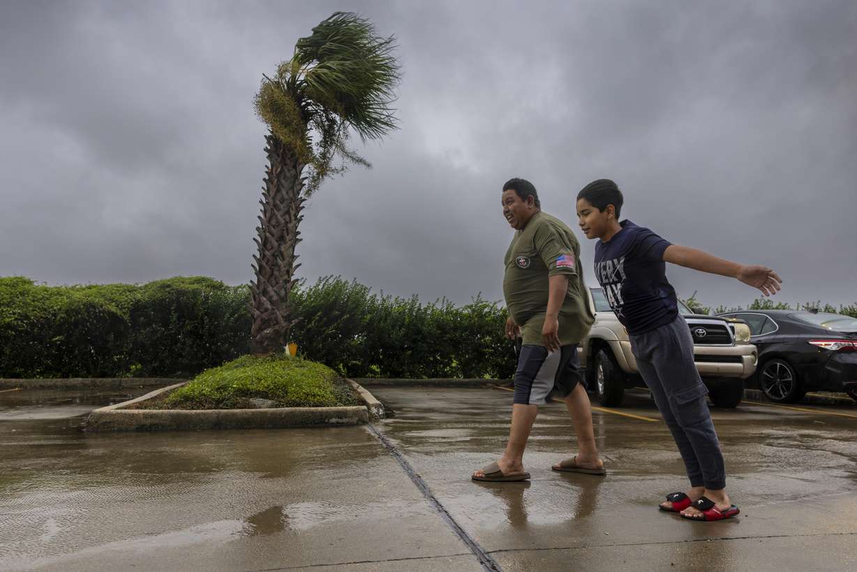 Lazaro Cardoso, 11, leans far into the powerful winds coming from the eye wall of Hurricane Francine as he and his dad, Hugo Gonzales, stay at a hotel Wednesday, in Houma, La., that was being powered by a generator.