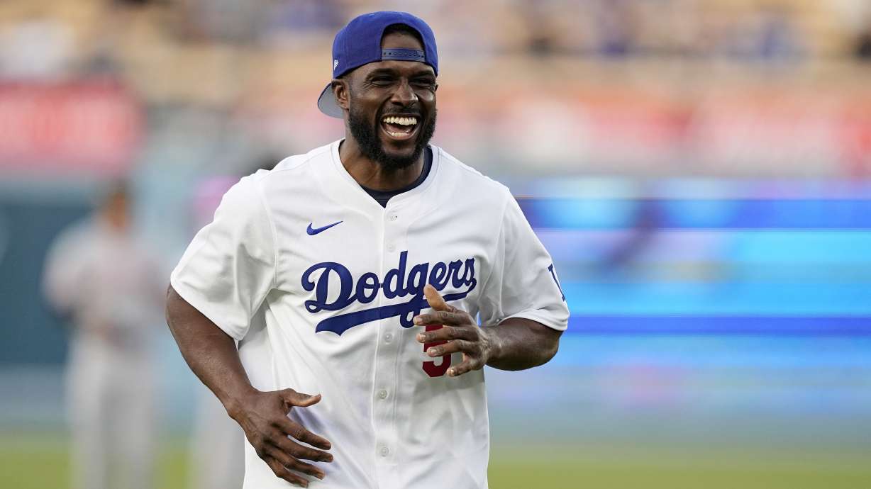 FILE - Former NFL and University of Southern California running back Reggie Bush, left, jokes with laughs after throwing out the ceremonial first pitch prior to a baseball game between the Los Angeles Dodgers and the Cincinnati Reds Friday, May 17, 2024, in Los Angeles.