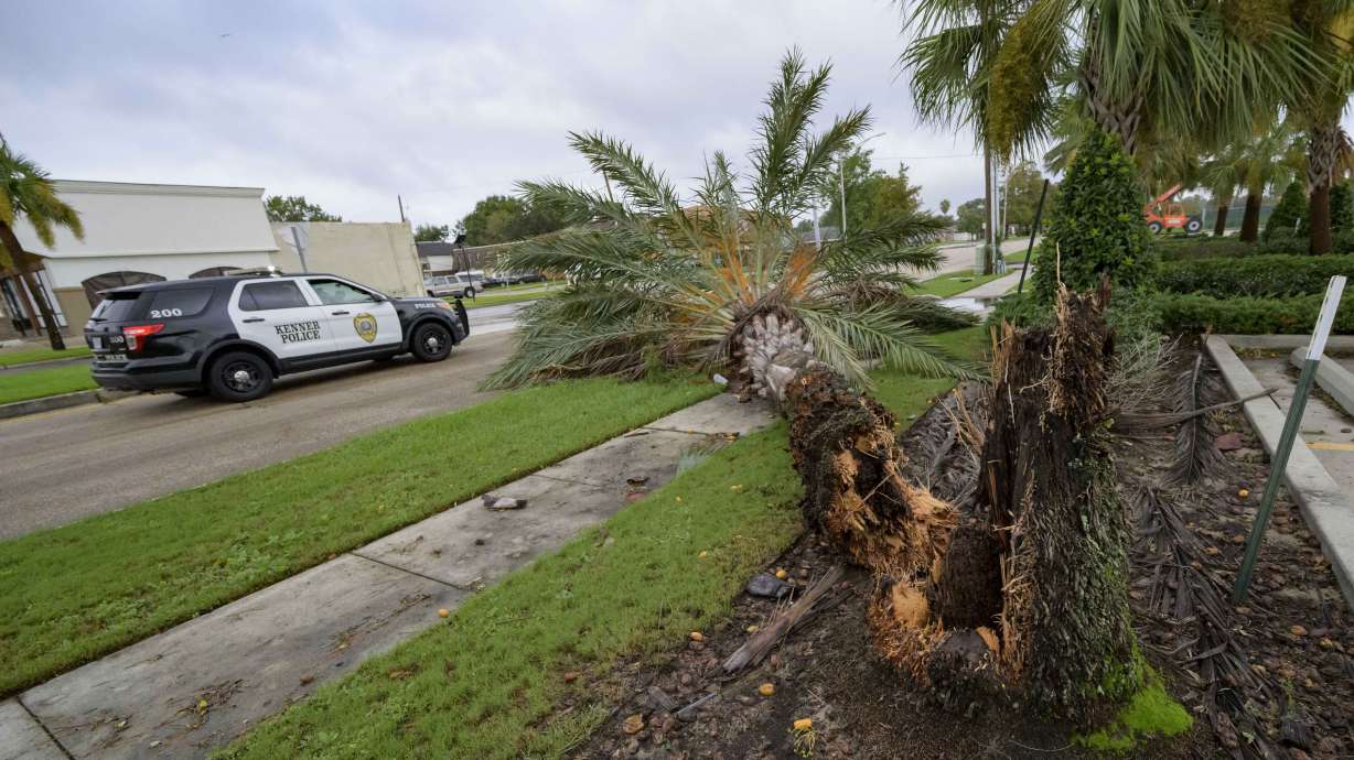 A Kenner police vehicle drives past a fallen tree after Hurricane Francine in Kenner, La., in Jefferson Parish, Thursday. Francine is weakening after striking Louisiana as a Category 2 hurricane. The system knocked out power to hundreds of thousands of homes and businesses.