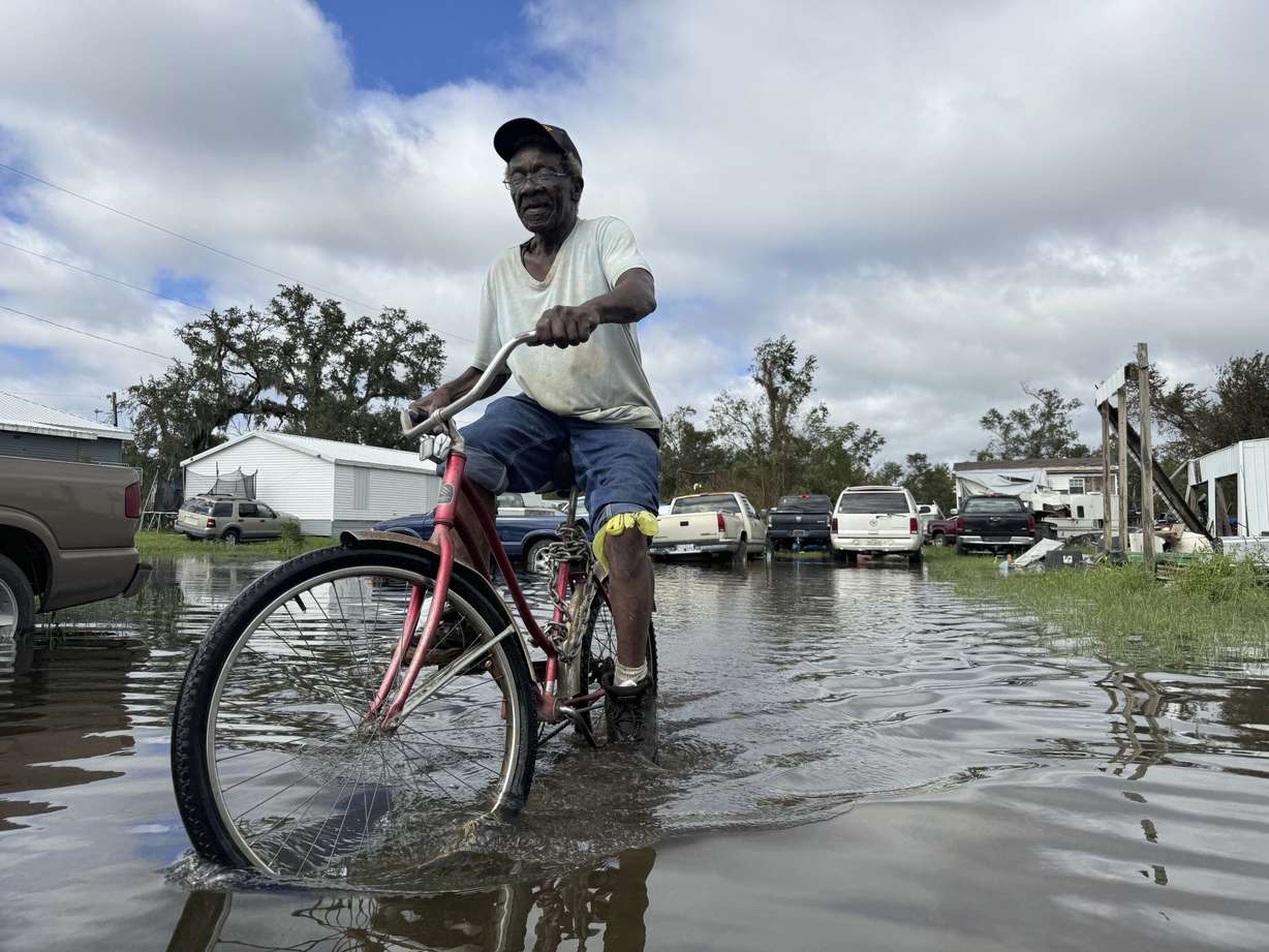 Carter Caldwell bikes through his family's flooded property just south of Houma, La. after Hurricane Francine tore through the area, Thursday.