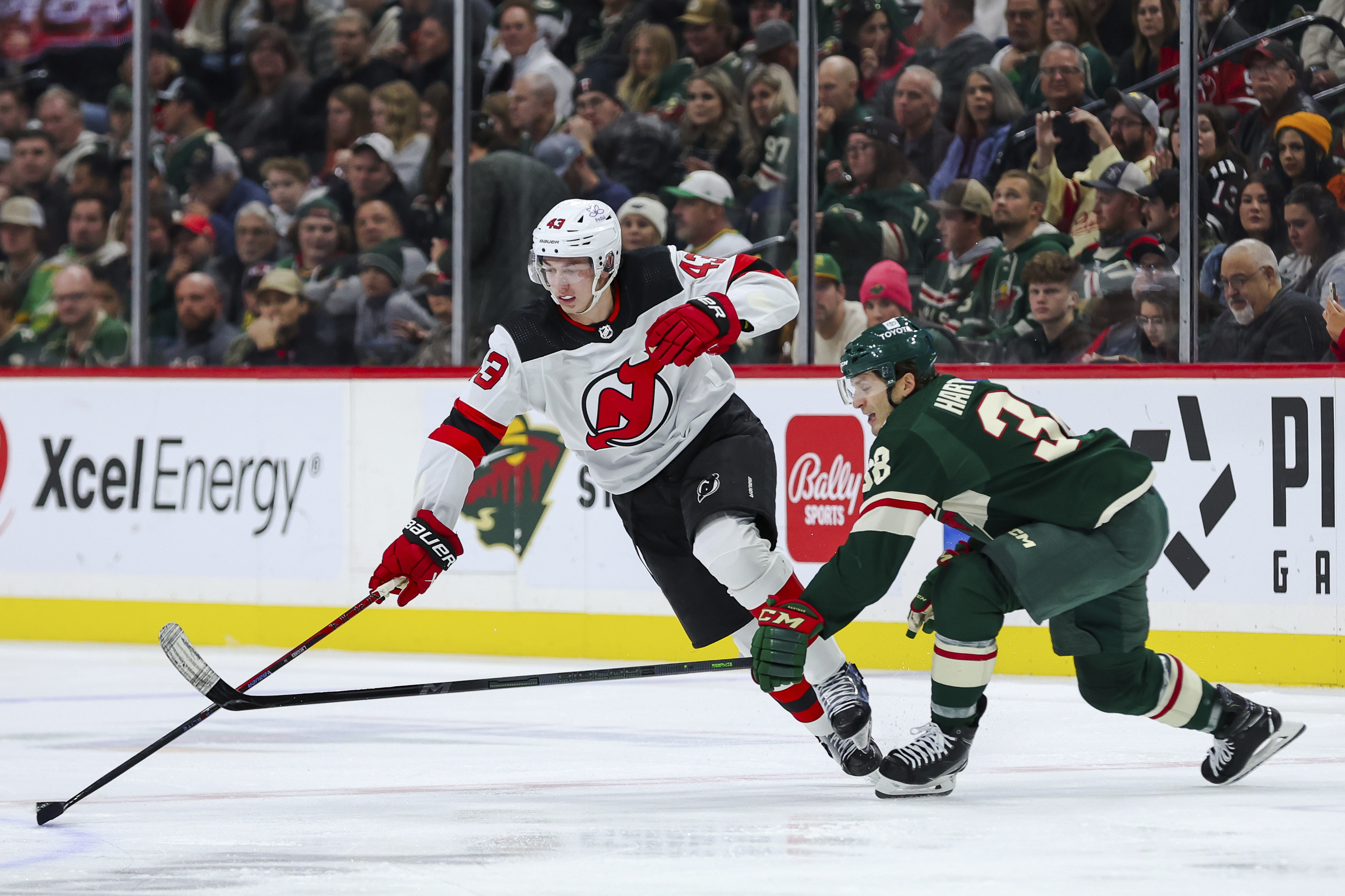 FILE - New Jersey Devils defenseman Luke Hughes, left, skates with the puck alongside Minnesota Wild right wing Ryan Hartman (38) during the second period of an NHL hockey game, Nov. 2, 2023, in St. Paul, Minn.