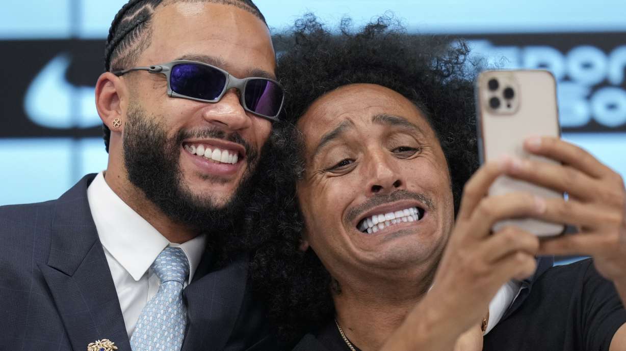 Soccer player Memphis Depay, of the Netherlands, left, poses for a selfie with TV reporter Papi during his media presentation as a new player for the Corinthians at Neo Quimica arena in Sao Paulo, Thursday, Sept. 12, 2024.