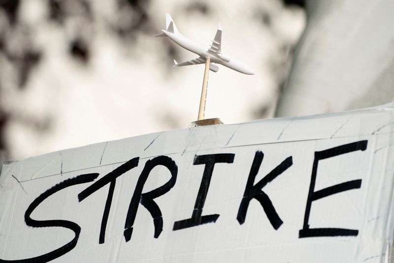 A worker holds a sign in support of a strike as Boeing factory workers wait in line to vote on their first full contract in 16 years, at an International Association of Machinists and Aerospace Workers District 751 union hall, in Renton, Wash., Thursday.