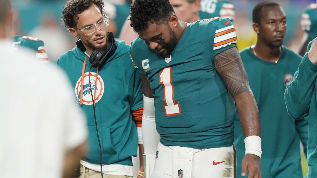 Miami Dolphins head coach Mike McDaniel talks to quarterback Tua Tagovailoa (1) as he leaves the game after suffering a concussion during the second half of an NFL football game against the Buffalo Bills, Thursday, Sept. 12, 2024, in Miami Gardens, Fla.