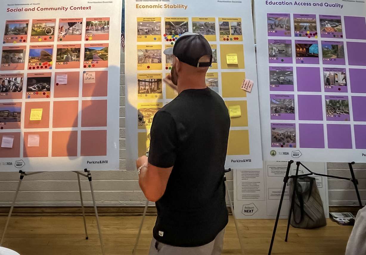 An attendee of a public meeting about the future plans for Smith's Ballpark places a sticker on specific project ideas possible for the stadium site during the event at the Urban Indian Center on Thursday.
