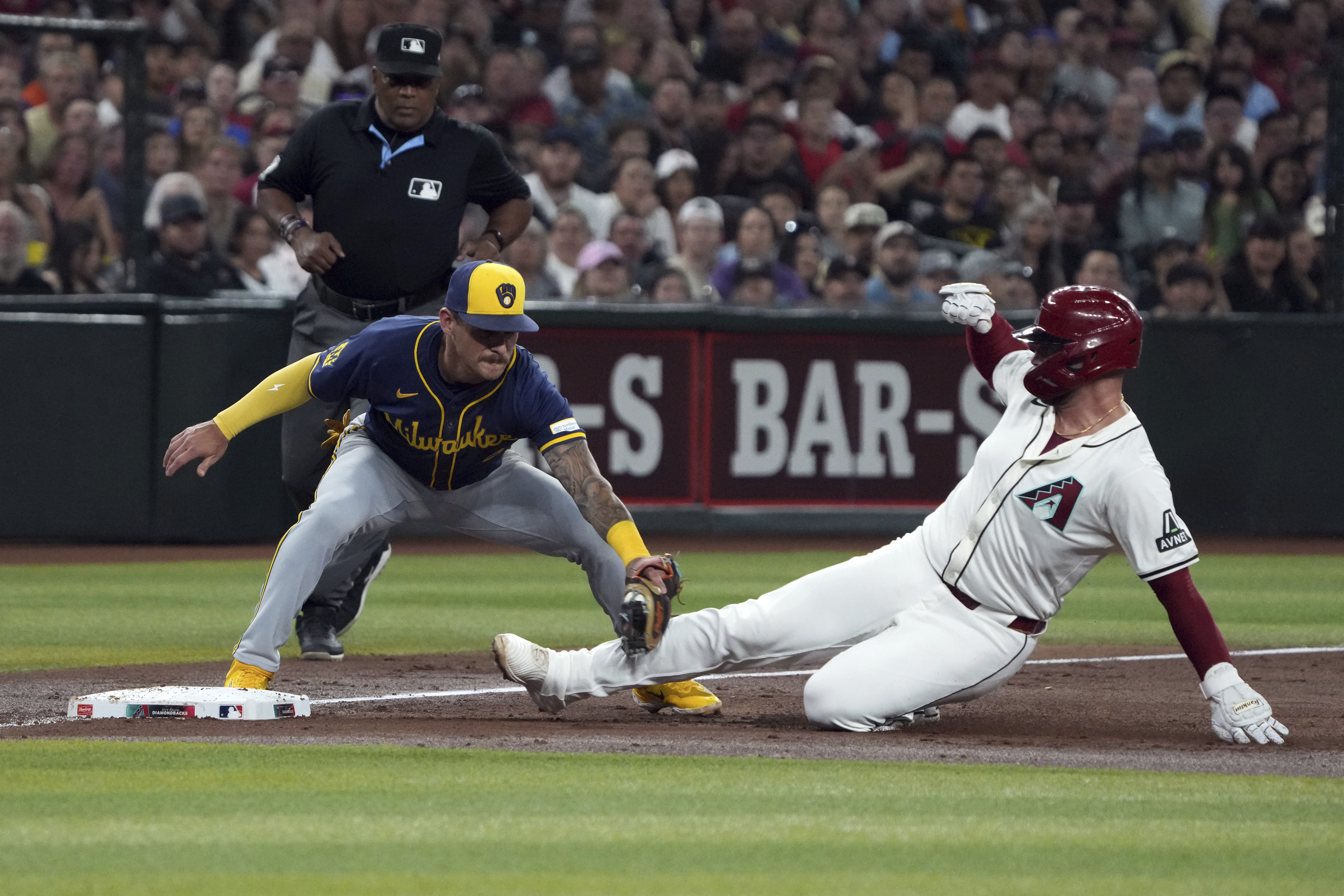 Milwaukee Brewers third base Joey Ortiz, left, tags out Arizona Diamondbacks' Christian Walker trying to advance in the third inning during a baseball game, Friday, Sept. 13, 2024, in Phoenix.