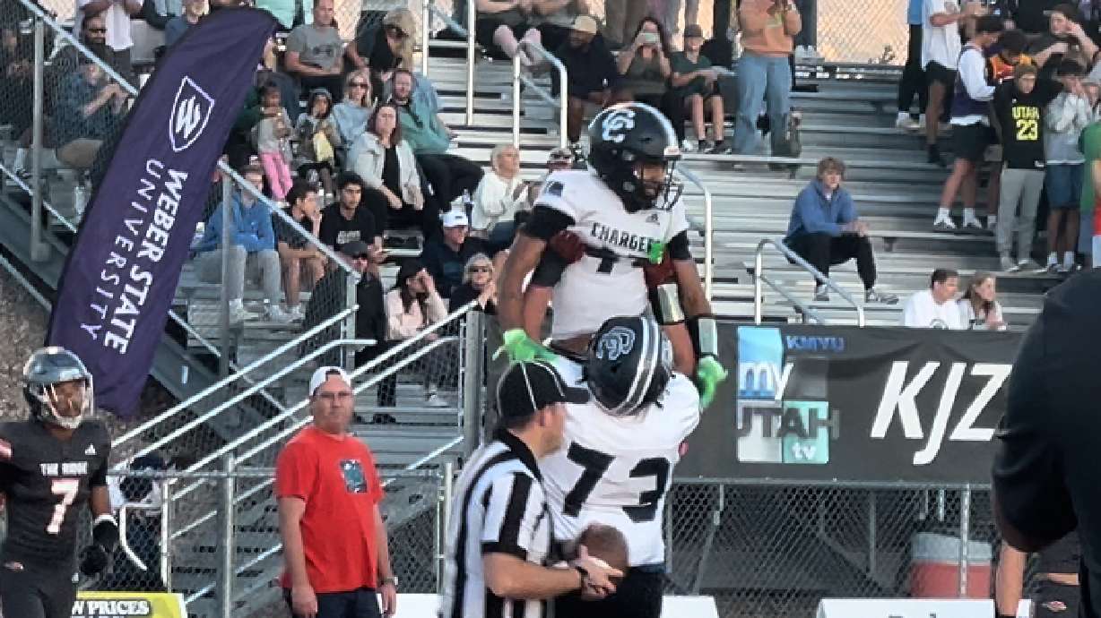 Chryshaun Lee, top, is lifted by Zion Finau to celebrated a Corner Canyon touchdown at Skyridge.