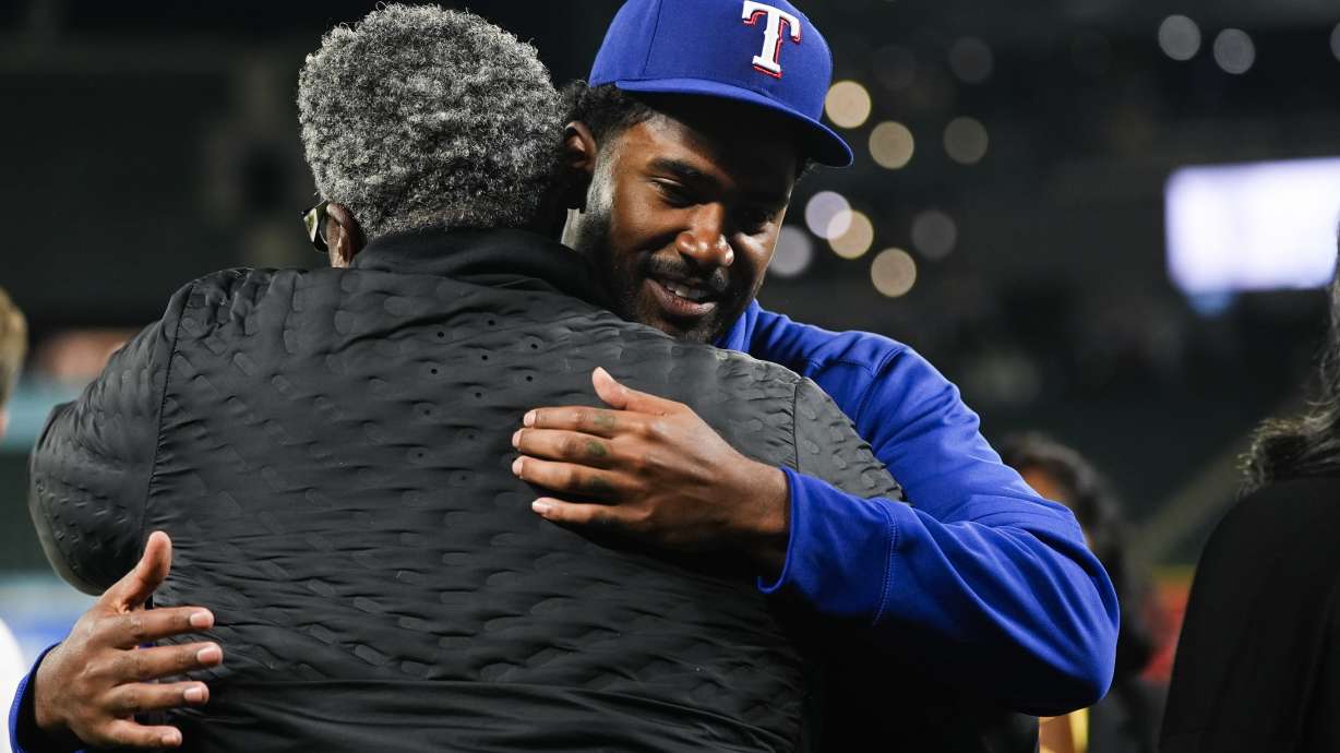 Texas Rangers starting pitcher Kumar Rocker, facing, greets his father and Tennessee Titans defensive line coach Tracy Rocker, after his major league debut in a 5-4 win over the Seattle Mariners in a baseball game Thursday, Sept. 12, 2024, in Seattle.