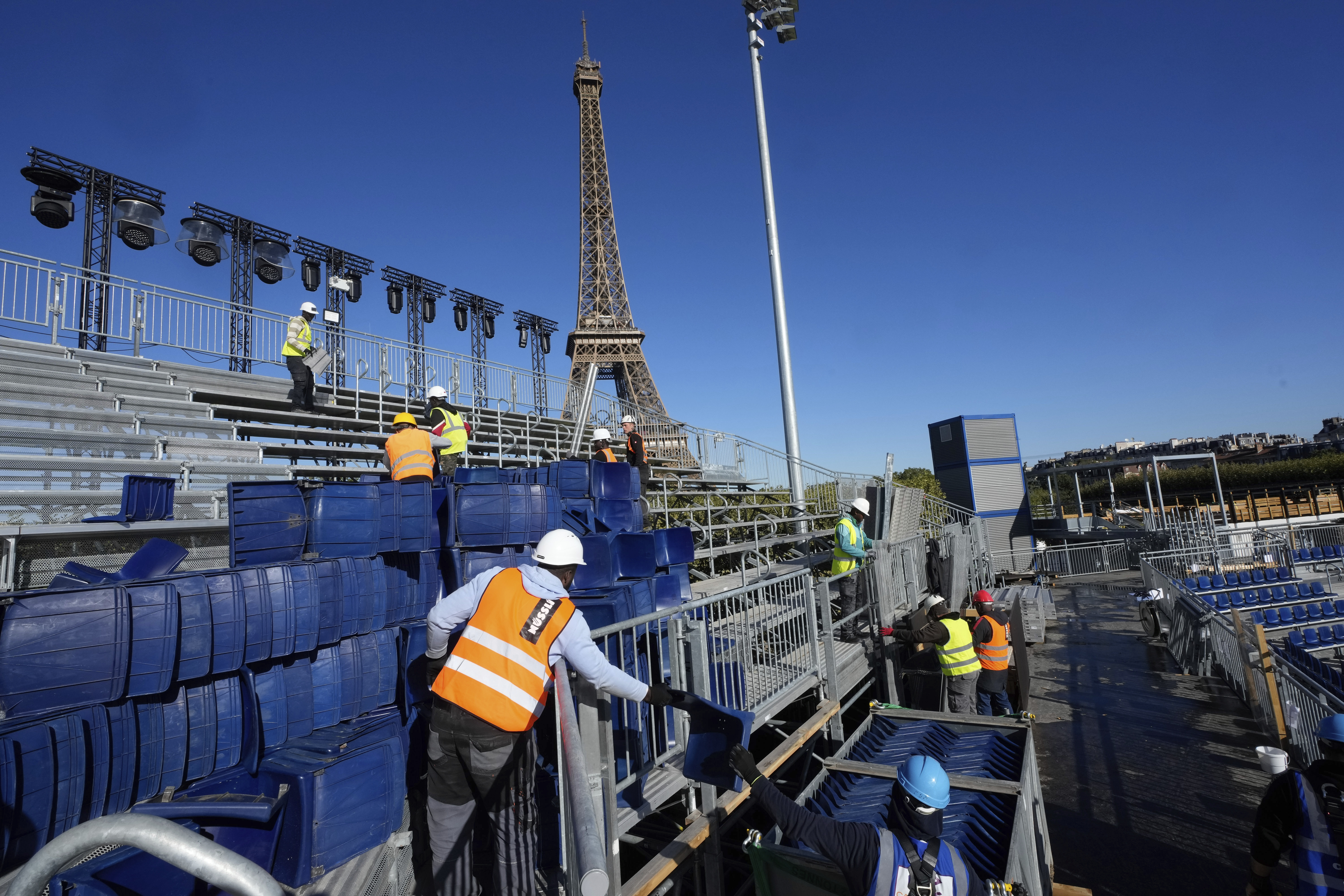 Workers remove grandstand seating as part of the dismantling of the Olympic venue the "Stade Tour Eiffel" with the Eiffel tower in the background in Paris, Friday, Sept. 13, 2024.
