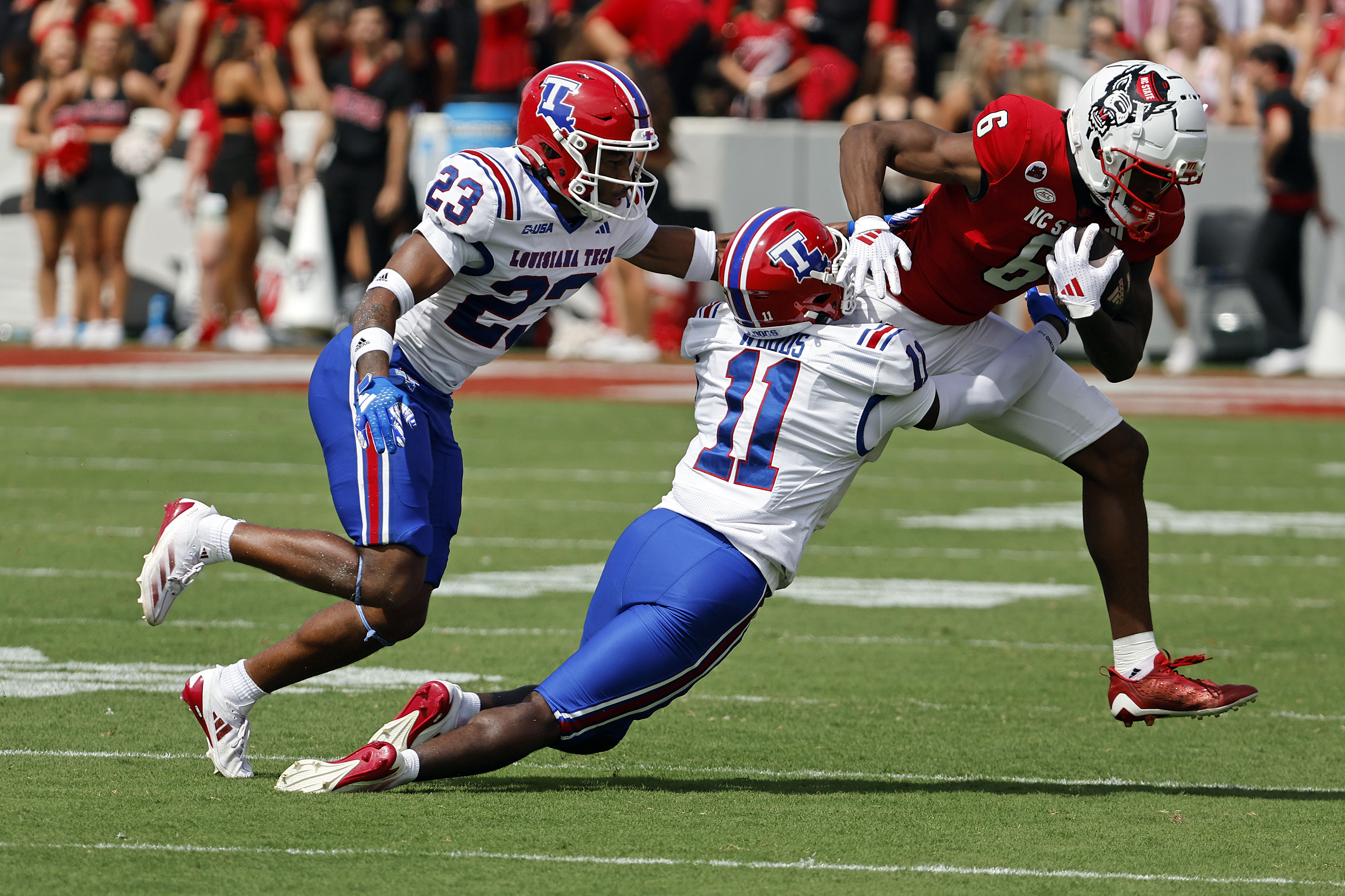 North Carolina State's Wesley Grimes (6) tries to break away from Louisiana Tech's Cedric Woods (11) and Jacob Fields (23) during the first half of an NCAA college football game in Raleigh, N.C., Saturday, Sept. 14, 2024.