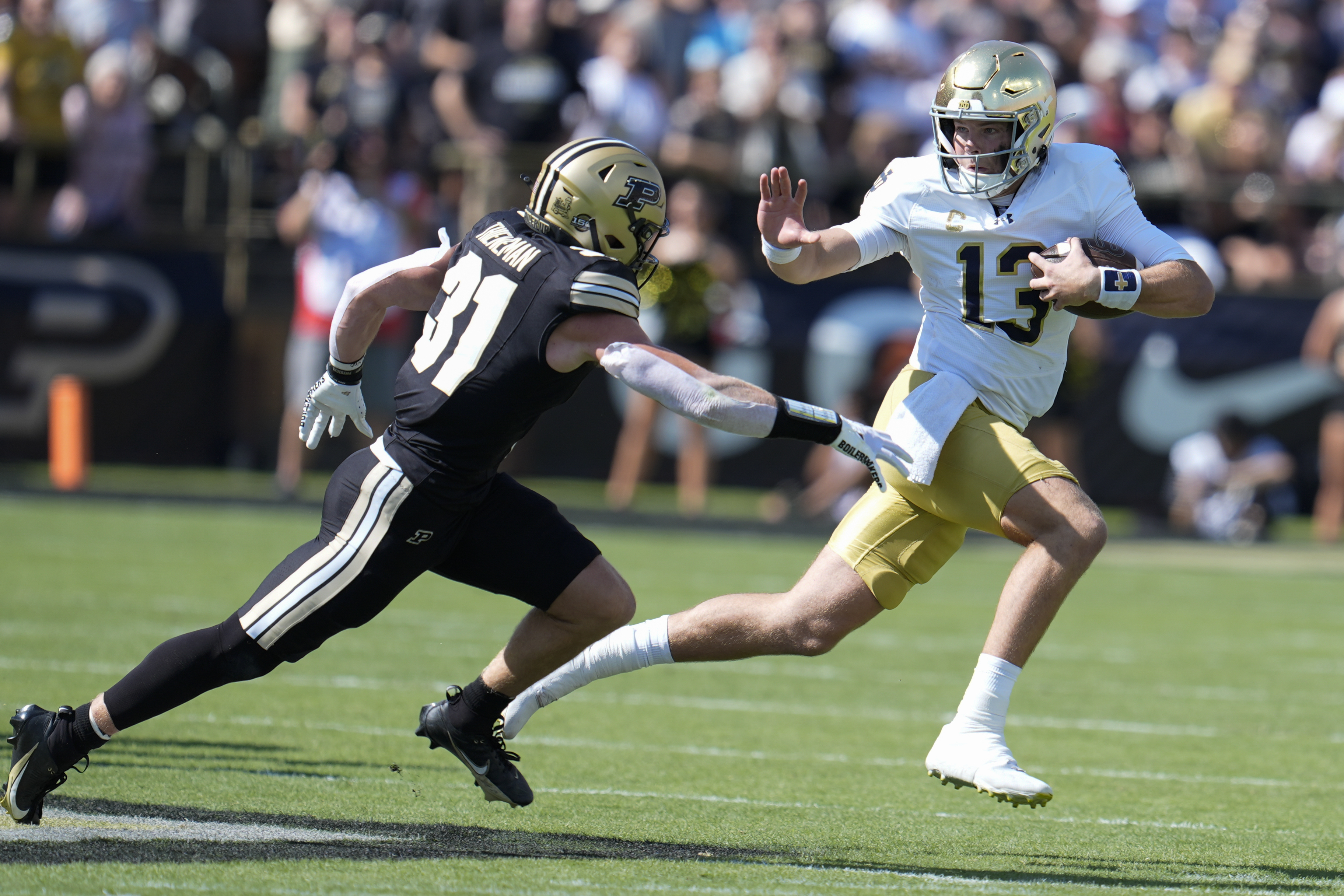 Notre Dame quarterback Riley Leonard (13) tries to get around Purdue defensive back Dillon Thieneman (31) during the first half of an NCAA college football game in West Lafayette, Ind., Saturday, Sept. 14, 2024.