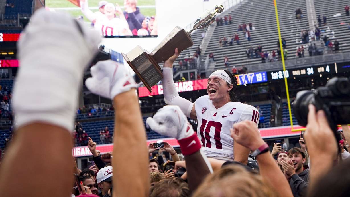 Washington State quarterback John Mateer holds up the Apple Cup trophy to celebrate a 24-19 win over Washington in an NCAA college football game Saturday, Sept. 14, 2024, in Seattle.