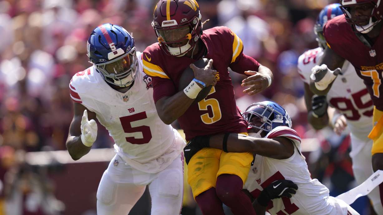 Washington Commanders quarterback Jayden Daniels (5) is tackled by New York Giants safety Jason Pinnock (27) during the first half of an NFL football game in Landover, Md., Sunday, Sept. 15, 2024.