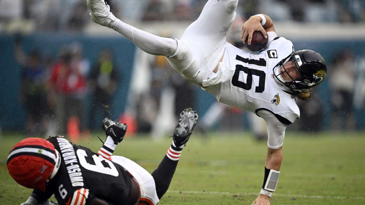 Jacksonville Jaguars quarterback Trevor Lawrence (16) leaps over Cleveland Browns linebacker Jeremiah Owusu-Koramoah (6) on a run during the second half of an NFL football game Sunday, Sept. 15, 2024, in Jacksonville, Fla.