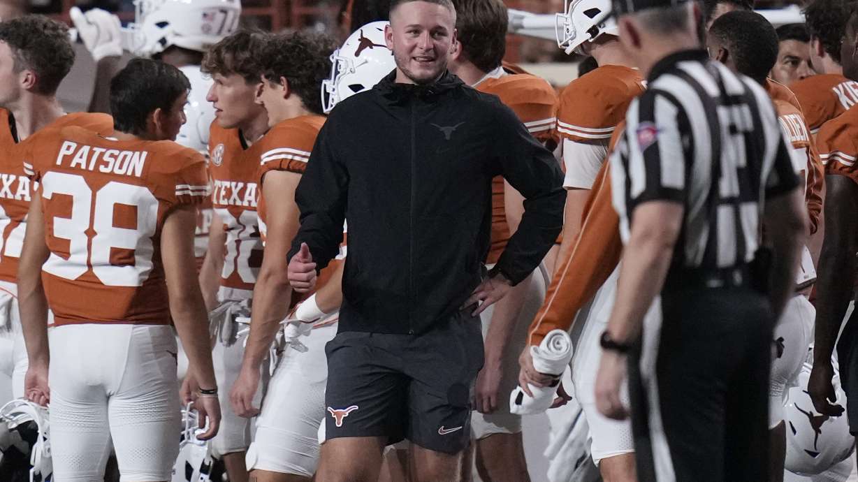 Texas quarterback Quinn Ewers, center, stands on the sidelines in street cloths after he was injured during the second half of an NCAA college football game against UTSA in Austin, Texas, Saturday, Sept. 14, 2024.