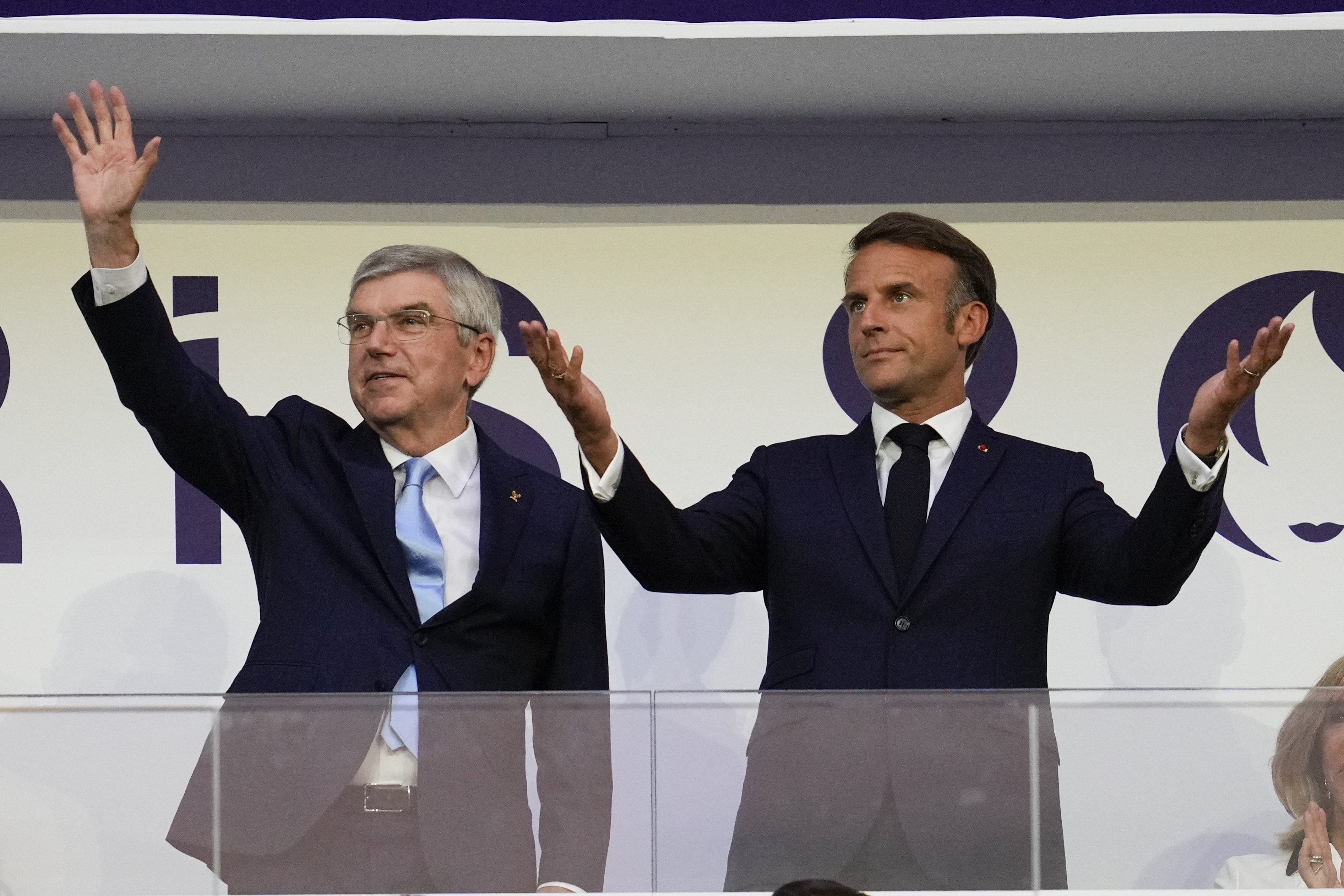 FILE - IOC President Thomas Bach and French President Emmanuel Macron wave during the 2024 Summer Olympics closing ceremony at the Stade de France, Aug. 11, 2024, in Saint-Denis, France.