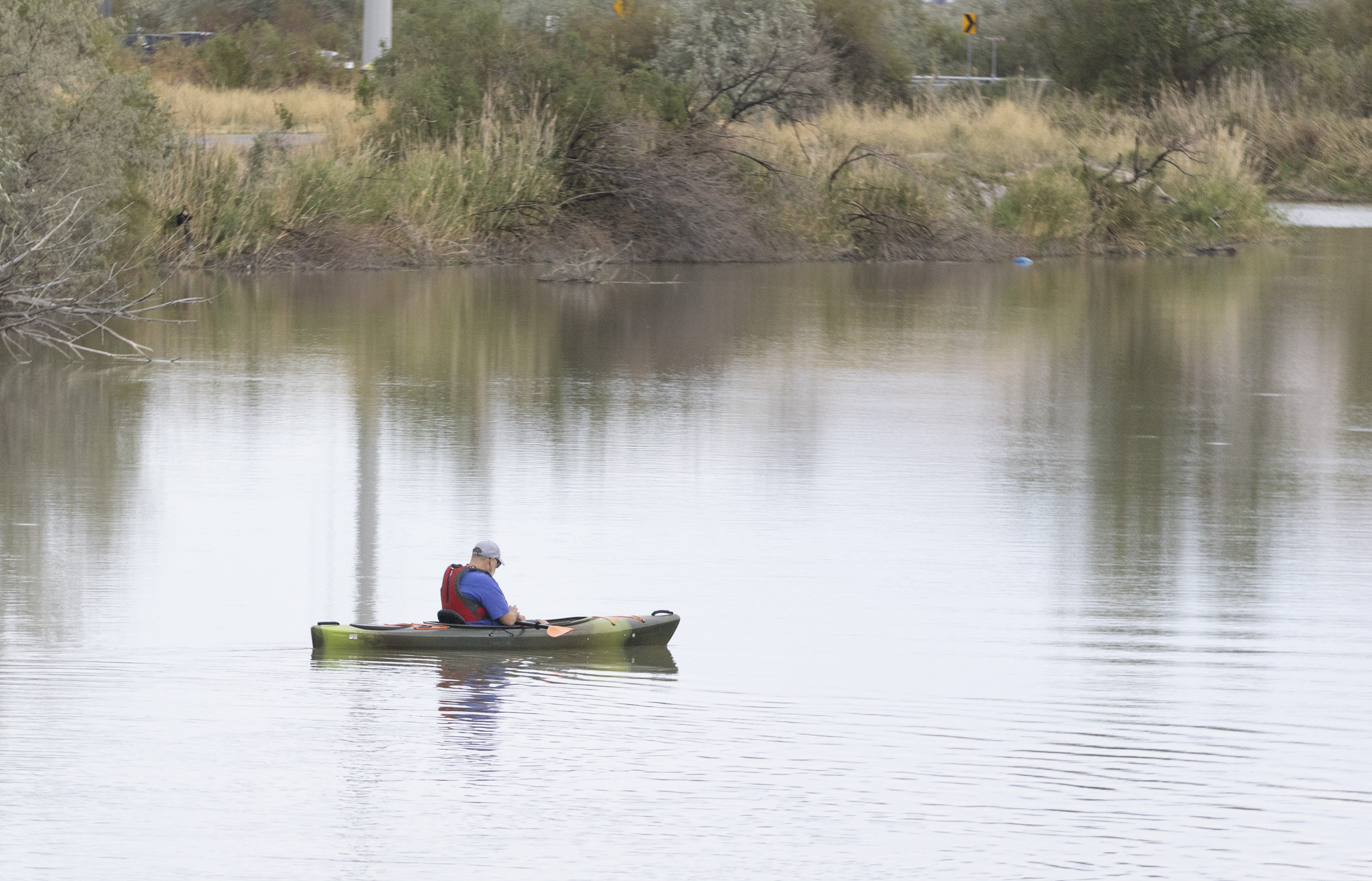 A kayaker can be seen floating in the headwaters of the Jordan River during a press conference held by the Great Salt Lake Watershed Enhancement Trust at the Utah Lake Control Gates at Inlet Park in Saratoga Springs on Monday.