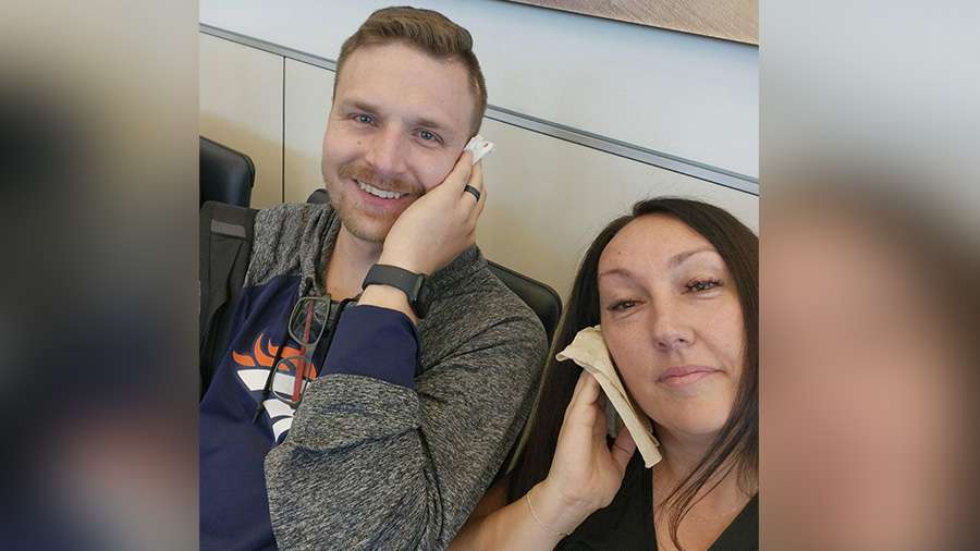 Jaci Purser and another passenger hold a cloth on their ears Sunday on board a flight that had cabin pressurization issues.