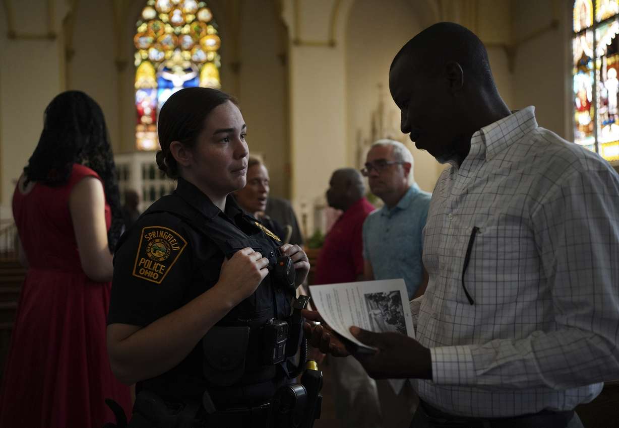 A Springfield police officer talks to a parishioner after a service in support of the Haitian community at St. Raphael Catholic church in Springfield, Ohio, on Sept. 15.