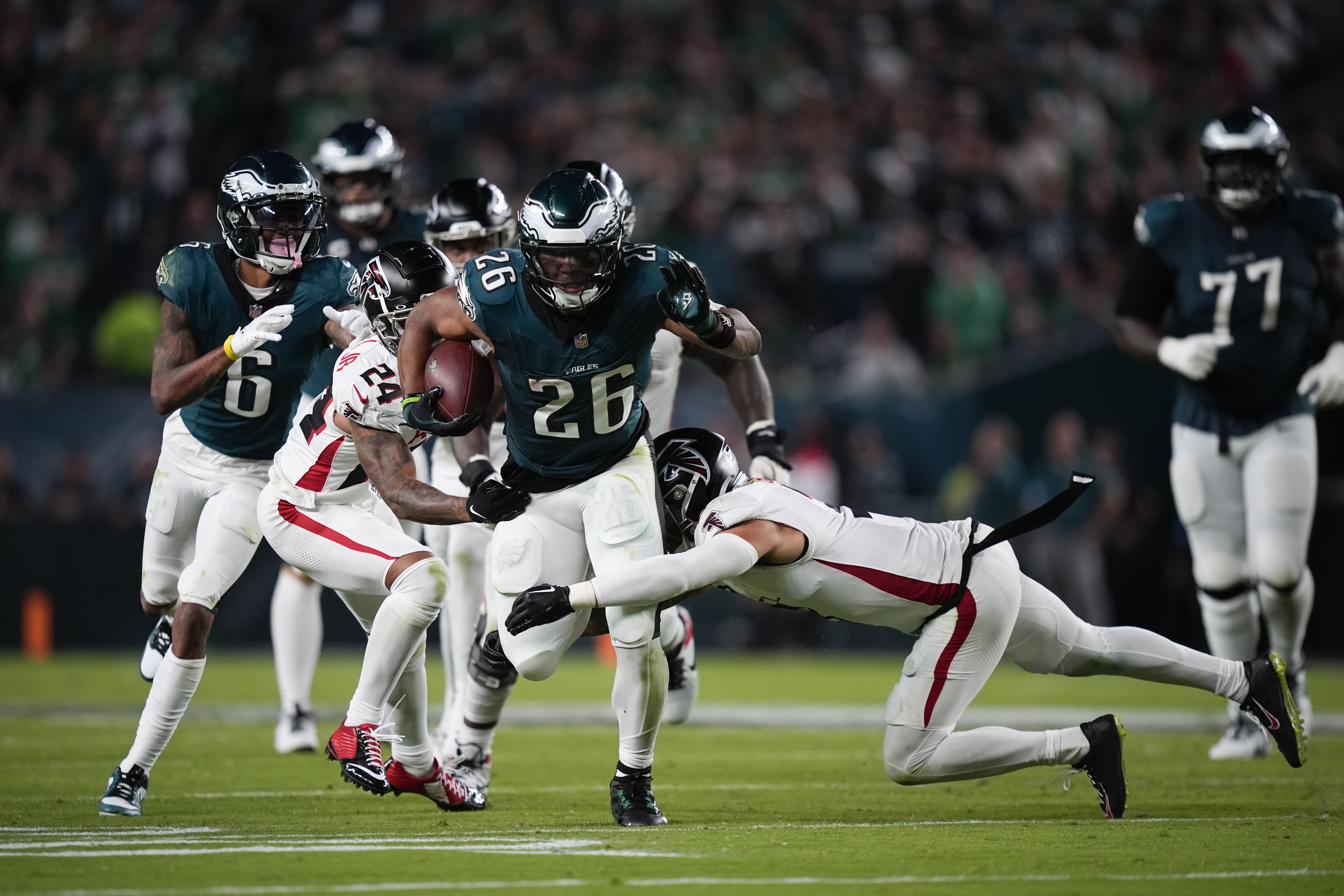 Philadelphia Eagles running back Saquon Barkley (26) runs with the ball under pressure from Atlanta Falcons cornerback A.J. Terrell (24) and Atlanta Falcons safety Jessie Bates III during the second half of an NFL football game on Monday, Sept. 16, 2024, in Philadelphia.