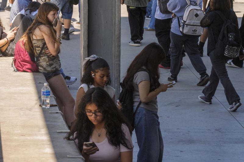 Students use their cellphones as they leave for the day the Ramon C. Cortines School of Visual and Performing Arts High School in downtown Los Angeles, Aug. 13.