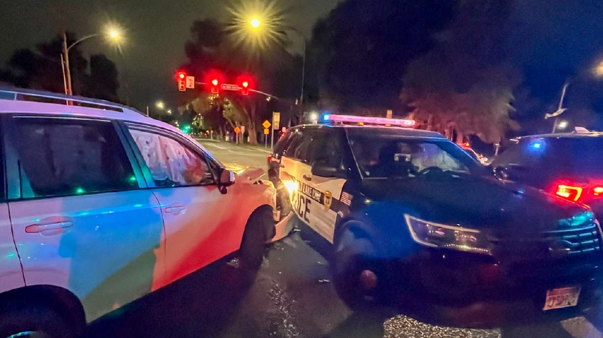 A 25-year-old man crashed into a line of parked police cars Tuesday morning, injuring two people and damaging three vehicles, investigators said.