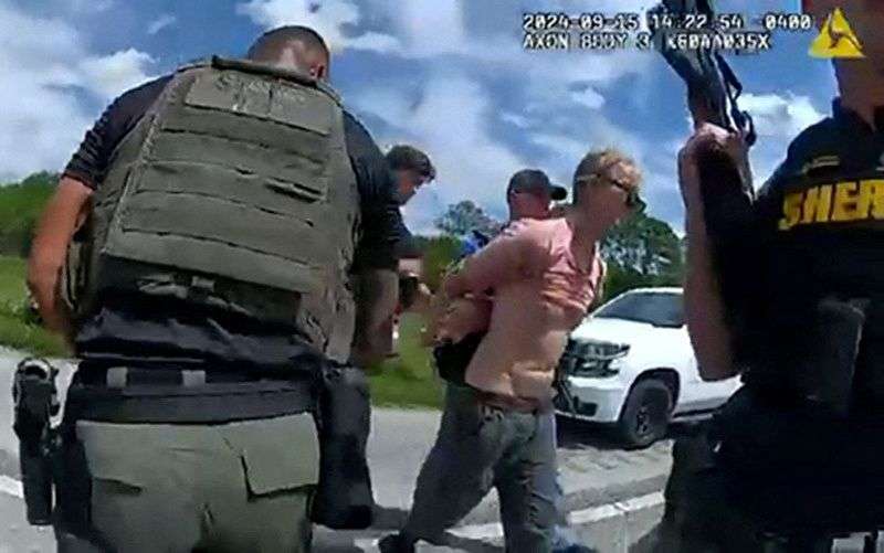 Ryan W. Routh, suspected of attempting to assassinate Republican presidential nominee and former President Donald Trump at his West Palm Beach golf course, is led by two Martin County Sheriff's Office deputies after his arrest during a traffic stop near Palm City, Fla, Sunday.