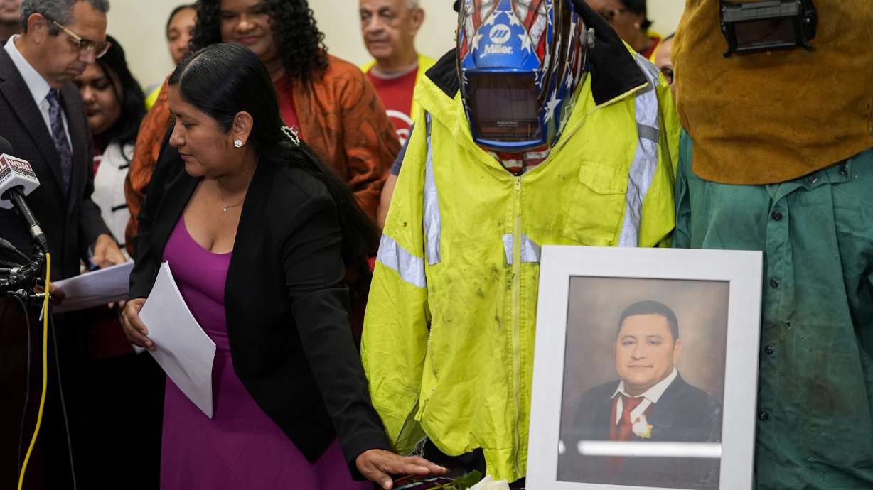 Maria del Carmen Castellón, the wife of Miguel Luna, a welder who died during the collapse of Baltimore's Francis Scott Key Bridge, places a rose near a portrait of her husband before speaking during a press conference, Tuesday in Baltimore.