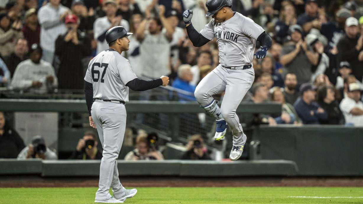 New York Yankees' Juan Soto, right, celebrates with third base coach Luis Rojas after hitting a two-run home run during the fourth inning of a baseball game against the Seattle Mariners, Tuesday, Sept. 17, 2024, in Seattle.