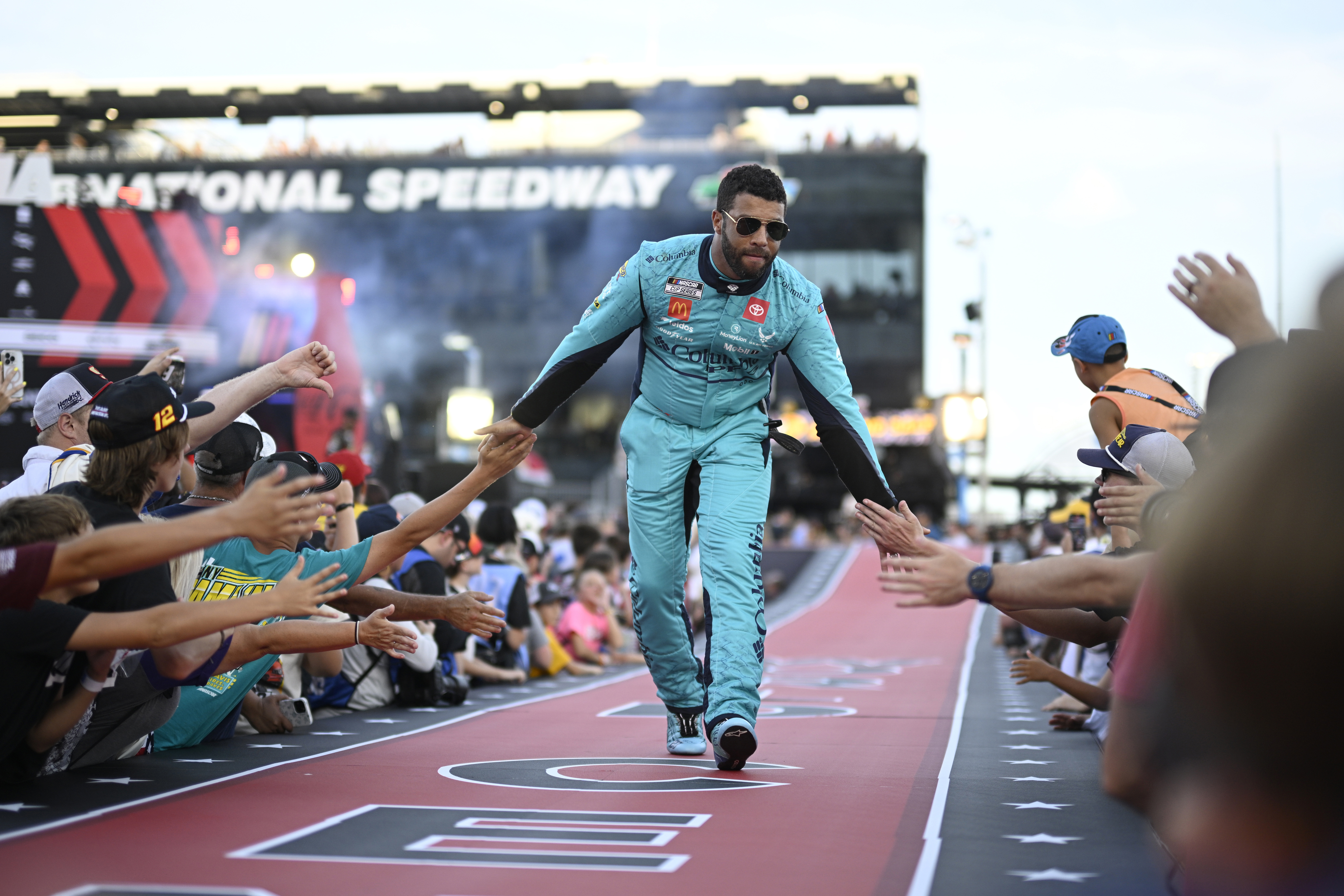 FILE - Bubba Wallace interacts with spectators while walking down a runway during driver introductions before a NASCAR Cup Series auto race at Daytona International Speedway, Aug. 24, 2024, in Daytona Beach, Fla.