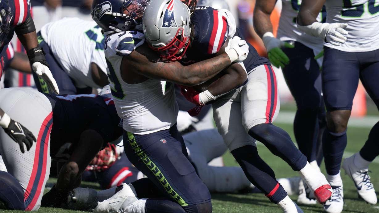 New England Patriots running back Rhamondre Stevenson, center right, runs into the end zone for a touchdown as Seattle Seahawks defensive end Leonard Williams, center left, defends in the second half of an NFL football game, Sunday, Sept. 15, 2024, in Foxborough, Mass.